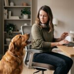 Dog barking for attention while owner works on a laptop at home.